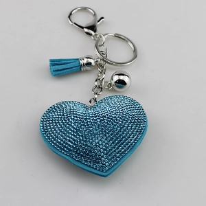 Close-up of sky blue heart keychain with sparkling rhinestones, tassel and small silver bell
