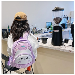 Rear view of a child wearing a purple cartoon cat backpack in a lifestyle cafe setting