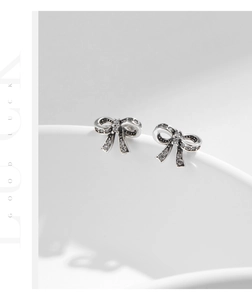 Macro view of detailed bowknot earrings featuring sparkling pave zircons and vintage silver finish