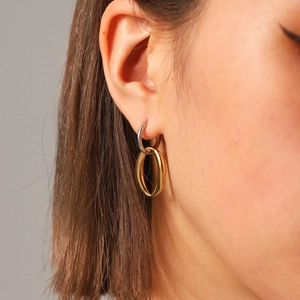 Minimalist two-tone stainless steel oval drop earrings worn by a model in a close-up view