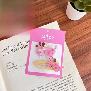 Close-up of cute cartoon acrylic pink polka dot puppy hair clips on a book page