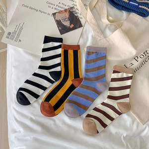 Set of four classic cotton striped crew socks in various colors on a white fabric background
