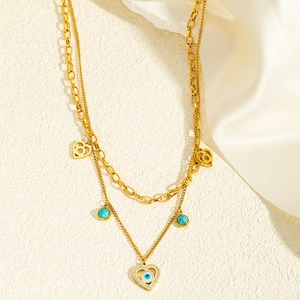 Détail du collier doré multicouche avec pendentif cœur œil protecteur et perles turquoise
