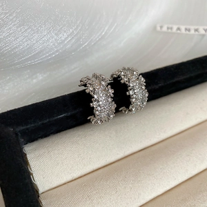 Détail macro de boucles d'oreilles argentées en C avec micro-cristaux sur velours noir