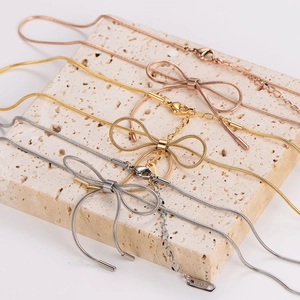 Minimalist stainless steel bow necklaces shown in silver, gold, and rose gold finishes
