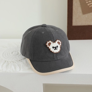Detailed view of grey kids baseball cap with bear patch and beige piped brim