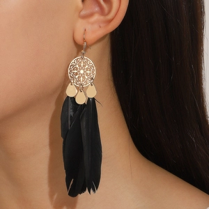 Detail of long bohemian earrings featuring black feathers and golden filigree metal