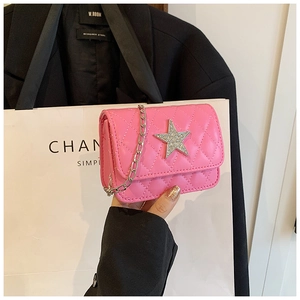 Detailed view of a pink quilted crossbody bag with a sparkling silver star and chain