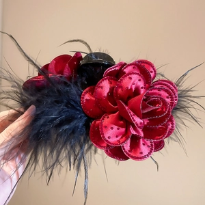 Detail of red fabric rose hair claw clip with black feathers and red rhinestones