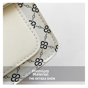 Détail macro du sac en cuir blanc grainé avec motif floral noir et surpiqûres précises