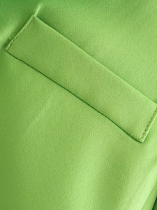 Macro shot of green crop top pocket detail with high-quality twill weaving texture