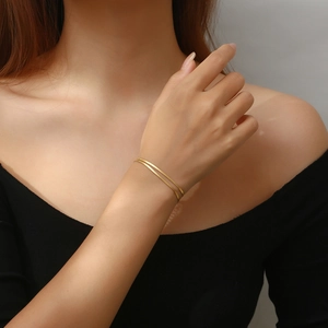 Detailed view of a gold double-layer snake bone chain bracelet on a model's wrist
