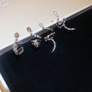 Close-up of silver snake earrings with pavé zircon stones on a black velvet display