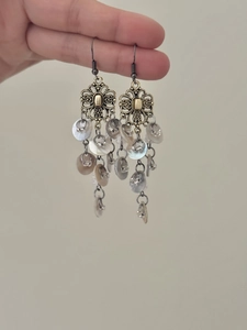 Detail of vintage hollow flower earrings with layered shell tassels held by hand