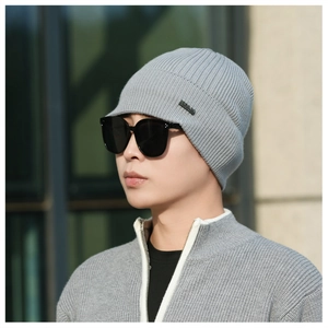 Detailed view of grey ribbed knit beanie with metallic logo plate and thick texture