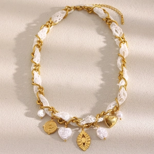 Detail of 18K gold-plated chain necklace with white lace and mixed symbolic charms