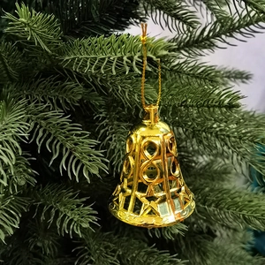 Nahaufnahme goldener hohler Weihnachtsklocken, die an einem Tannenbaum hängen