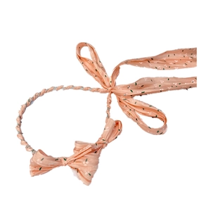 Detail of peach fabric headband with floral pattern and long flowing bow ribbons