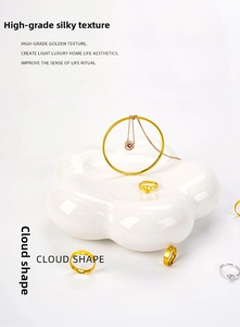 Glossy white ceramic flower tray showcasing a curated jewelry collection from a top view