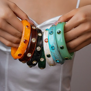 Macro view of colorful acrylic bangles with crystal inlay and gold metal base
