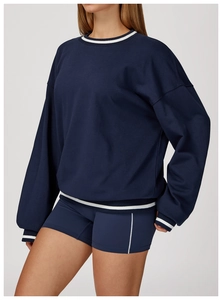 Detail view of navy blue sweatshirt with contrast white ribbing on collar and cuffs