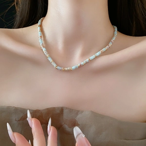 Ethnic beaded Shoushan stone necklace with blue and gold beads on a model's neck