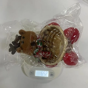 Detail of Christmas plush bear candy basket with festive knit scarf on a digital scale