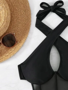 Detail of sexy black halter swimsuit with mesh patchwork and crossover bow design