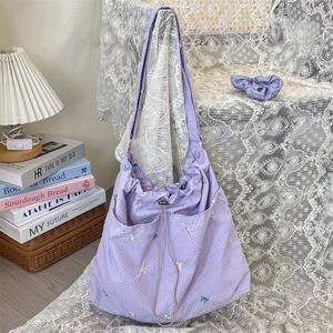 Detailed close-up of purple plaid drawstring bag with cute embroidered butterfly bow