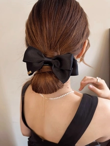 Rear view of model wearing a large black satin bow hair claw clip in a low bun hairstyle