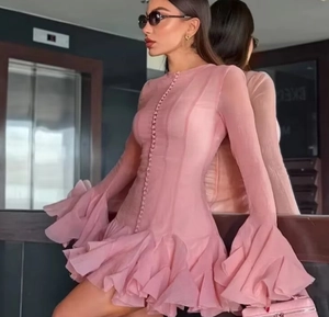 Detail of pink long-sleeved dress featuring layered ruffle cuffs and button decorations