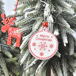 Detail of wooden reindeer and Merry Christmas ball ornaments on a snowy pine branch