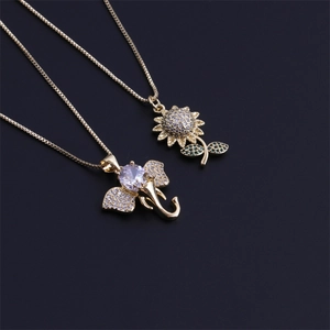 Détail macro de pendentifs éléphant et tournesol dorés avec des pierres en zircone cubique