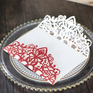 Detail of red glitter laser-cut invitation envelope and white insert card on glass tray