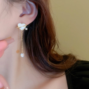 Elegant gold heart earrings with Saturn ring design and dangling tassel on model
