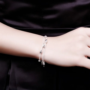 Elegant multi-strand silver plated beaded bracelet on a wrist against black fabric