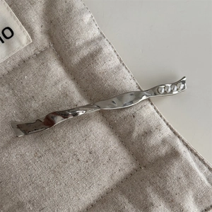Detailed macro view of silver metallic twisted hair clip with five elegant white pearls