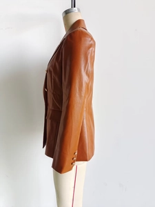 Detailed close-up of a caramel PU leather blazer featuring elegant gold metal buttons