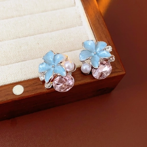 Gros plan de boucles d'oreilles vintage fleurs en émail bleu avec gouttes de cristal rose
