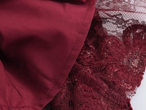 Close-up of red fabric texture with delicate lace trim and precise stitching details