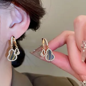 Golden Wulu drop earrings with shimmering pavé diamonds and vintage tiger eye inlay