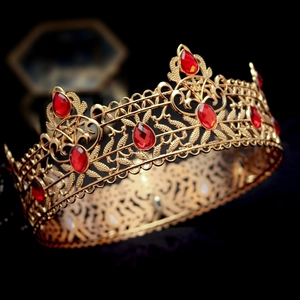 Close-up of vintage baroque golden crown with red crystal embellishments and leaf patterns