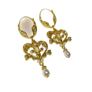 Elegant gold vintage tassels earrings with white stones and imitation pearls on white background