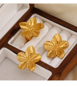 Detailed macro view of golden metal flower ring and earrings in a velvet jewelry box