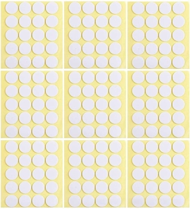 Macro detail of bulk white adhesive dots for candle wicks on yellow backing paper