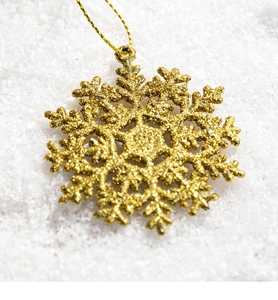 Close-up of a golden glitter snowflake ornament with a gold string for Christmas decor