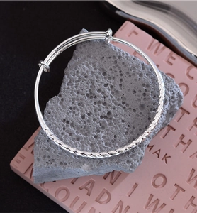Detailed macro view of silver hammered metal texture and diamond-cut pattern on the bangle