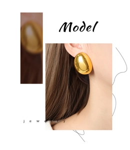 Detailed view of large gold oval stud earrings in mirror-polished finish on a model
