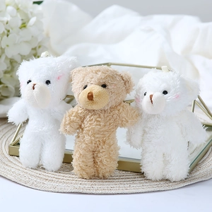 Detailed view of three plush teddy bear charms with pink blush and soft curly fur