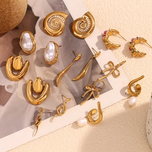 Flat lay of French vintage gold shell, baroque pearl, and snake-shaped earrings collection